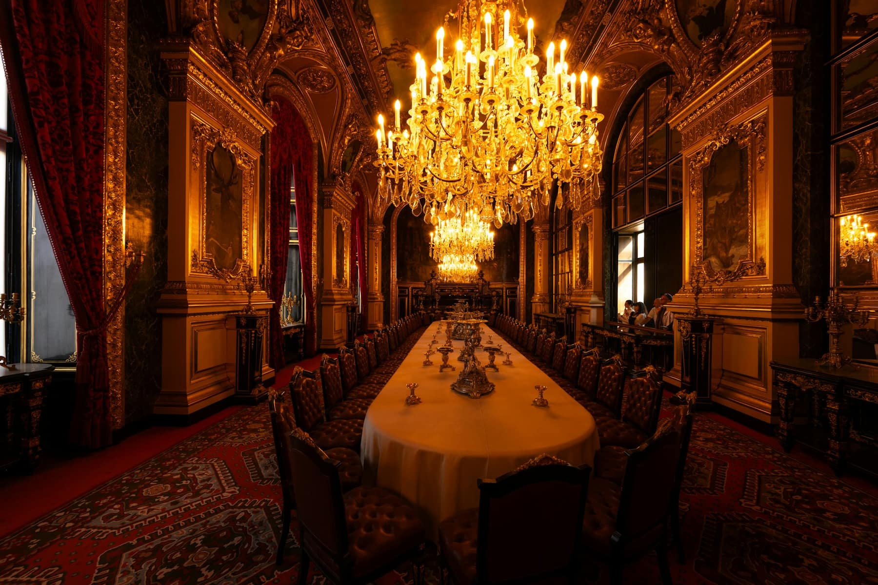Une longue table dressée sous des lustres dorés